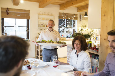 Happy senior man serving fish for family at christmas dinner