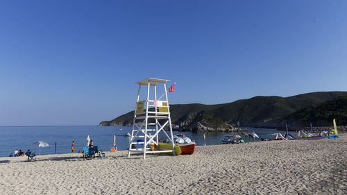 Lifeguard hut on beach against clear blue sky