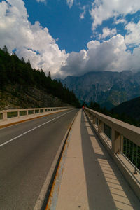 Empty road leading towards mountains against sky