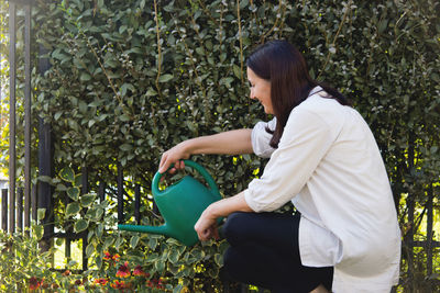 Woman crouching while watering plants