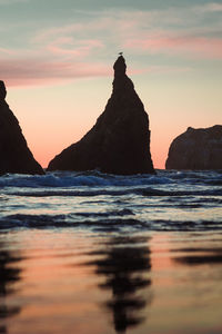 Rock formations in sea against sky during sunset