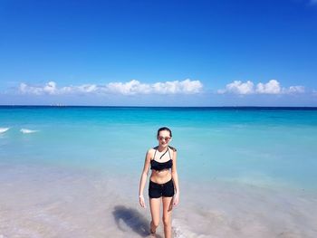 Teenage girl walking on shore at beach against sky