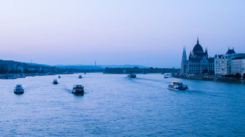 Boats sailing in river against clear sky