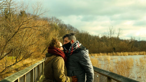 Midsection of couple kissing against sky during winter
