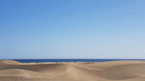Scenic view of beach against clear blue sky