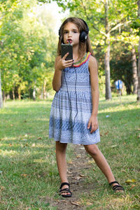 Smiling girl listening music while standing at park