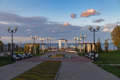 Street lights by footpath in city against sky