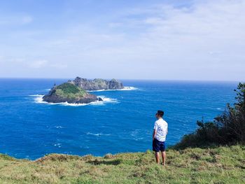 Rear view of man looking at sea against sky