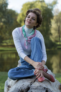 Portrait of smiling young woman standing against trees