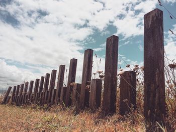 Wooden posts against cloudy sky