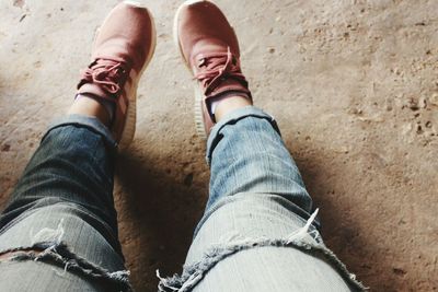 Low section of woman wearing shoes and torn jeans