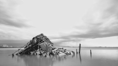 Wooden posts in sea against sky