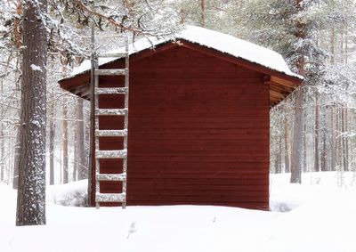 Snow covered houses by trees and buildings during winter