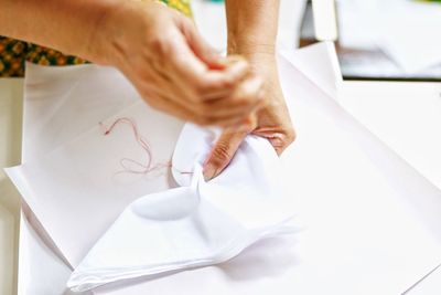 Midsection of woman sewing fabric on table