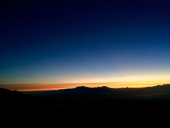 Scenic view of silhouette mountains against clear sky at sunset