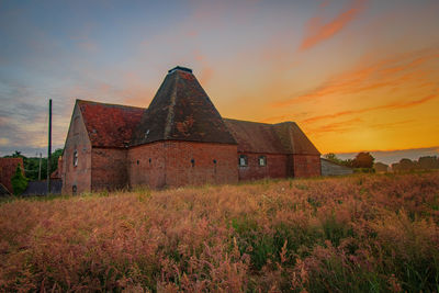 Old building on field against sky during sunset