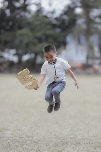 Full length of boy with number 5 balloon in mid-air