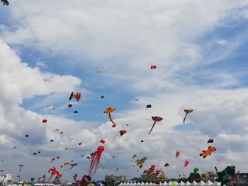Low angle view of kites flying against cloudy sky