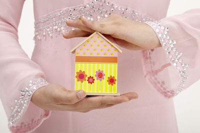 Midsection of woman holding model home against white background