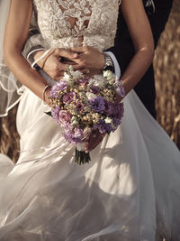 Midsection of bride holding bouquet