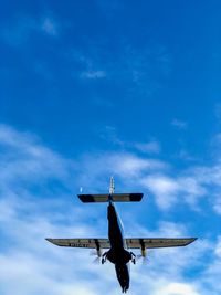 Low angle view of airplane flying against blue sky