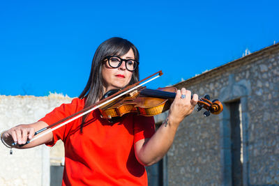 Woman playing violin against sky
