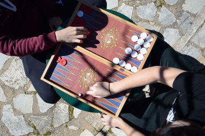 Midsection of friends playing board game while sitting outdoors