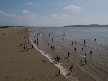 People playing at beach against sky