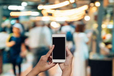 Cropped hand of woman using smart phone in city