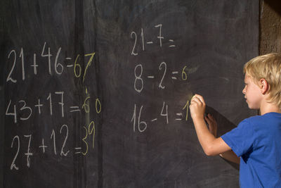 Boy solving mathematics on blackboard
