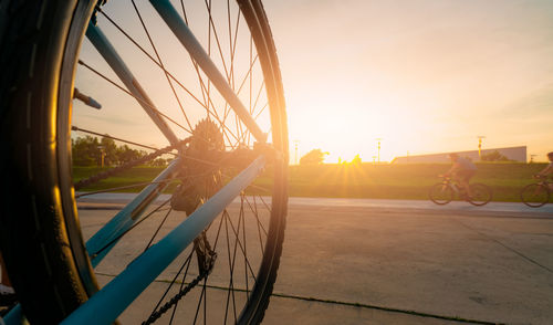 Bicycle by street against sky during sunset