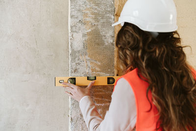 Professional architect woman in construction site using level tool on wall. home renovation