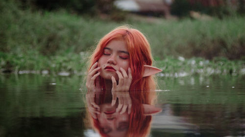 Portrait of young woman standing against lake