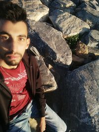 Portrait of young man sitting on rock