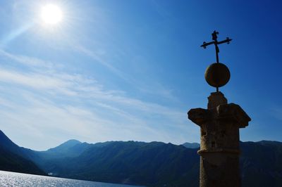 Low angle view of cross against sky at kotor bay on sunny day