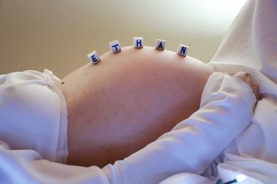 Midsection of toy blocks on pregnant woman stomach sleeping on bed