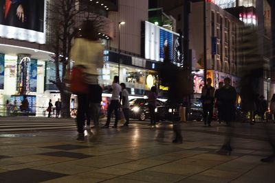 People walking on illuminated street at night