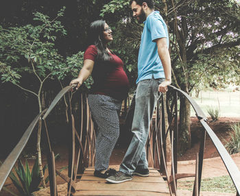 Young couple standing against trees