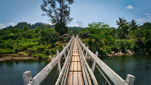 Footbridge over river against sky