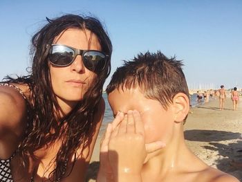 Portrait of woman with son at beach during sunny day