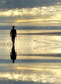Man on beach against sky during sunset