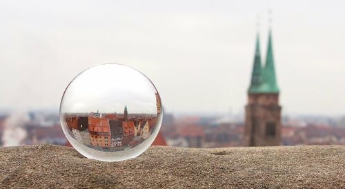 Crystal ball on retaining wall by st lorenz church against sky