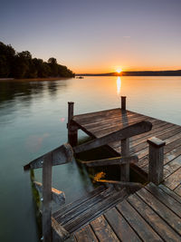 Wooden pier over lake against sky during sunset