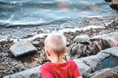 Rear view of boy on rock at beach