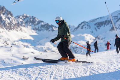 People skiing on snowcapped mountain against sky