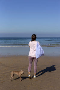 Rear view of woman with dog on beach