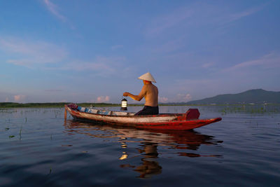 Man on boat in sea against sky