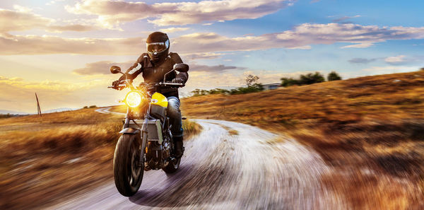 Man riding motorcycle on road against sky