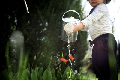 Little boy watering plants in the garden in spring on a sunny day