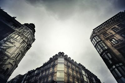 Low angle view of buildings against cloudy sky